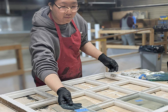 A person placing glass in a window frame.