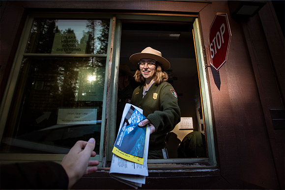 A ranger handing out a newspaper.