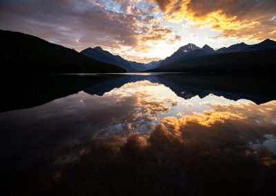 A sunrise with mountains reflecting on a lake.