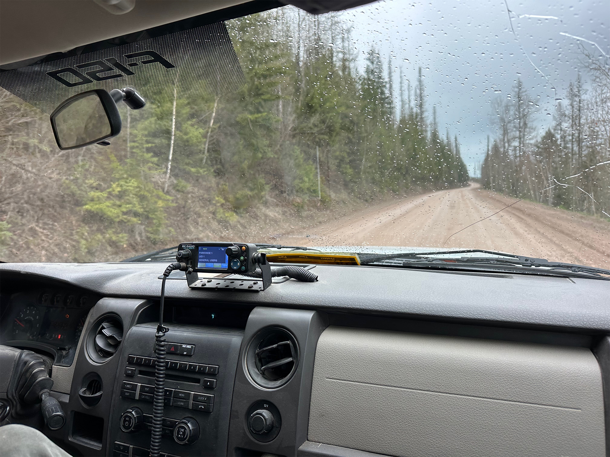 View out the front of a truck on a dirt road.