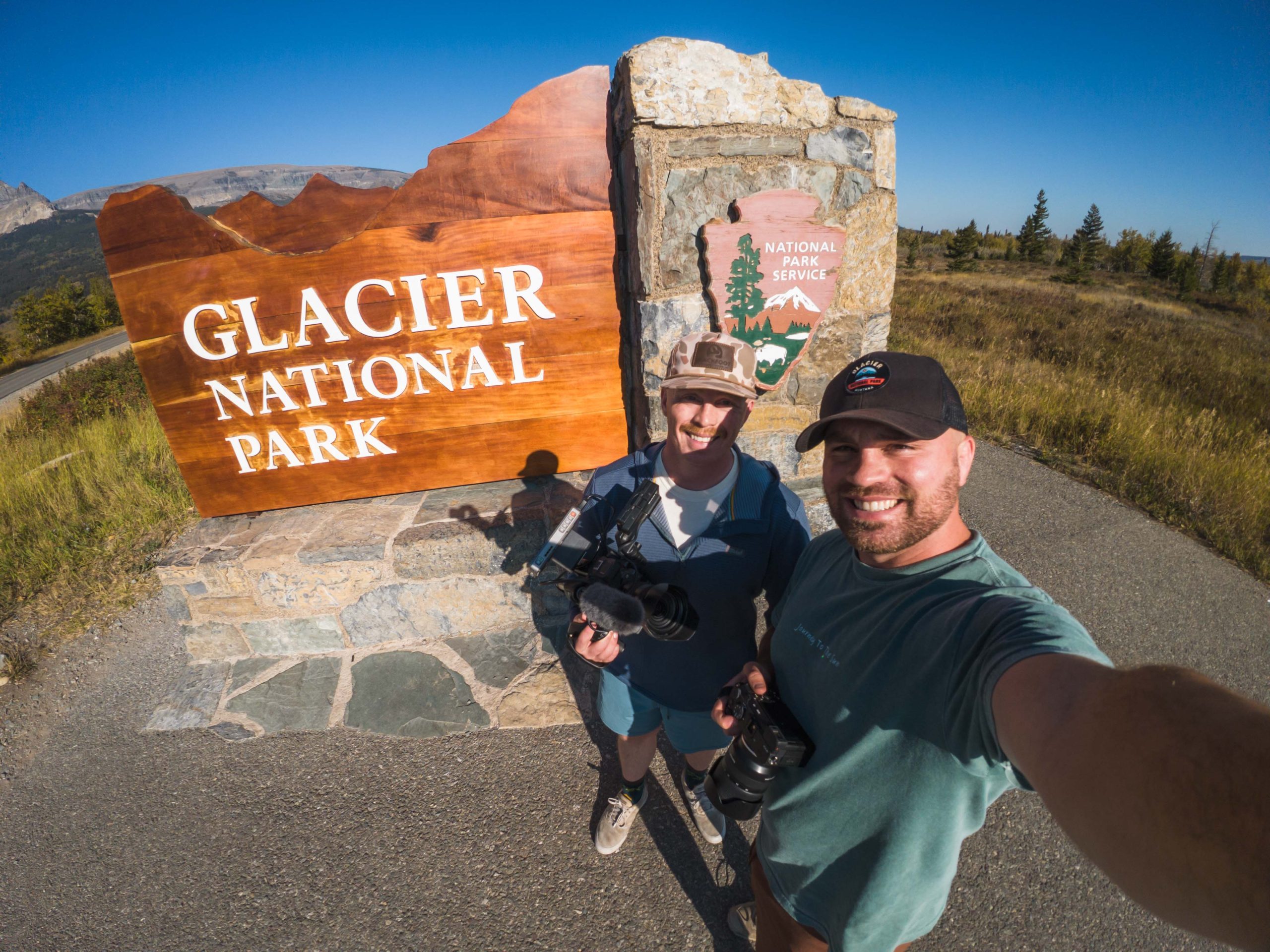 Jordan and Logan pose in front of park sign with cameras.