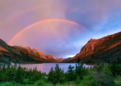 A double rainbow above a lake and mountains.