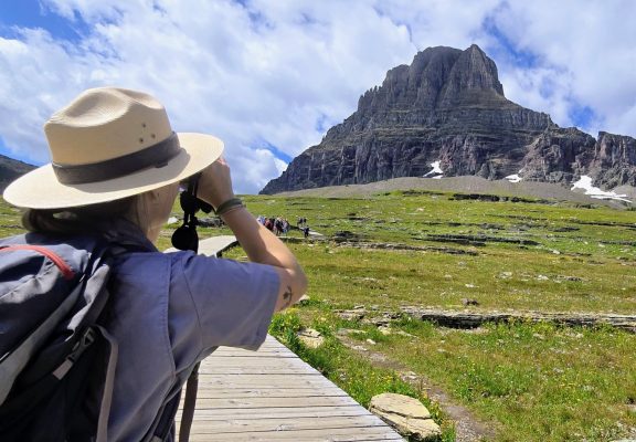 A ranger looks up the Hidden Lake Trail with binoculars.