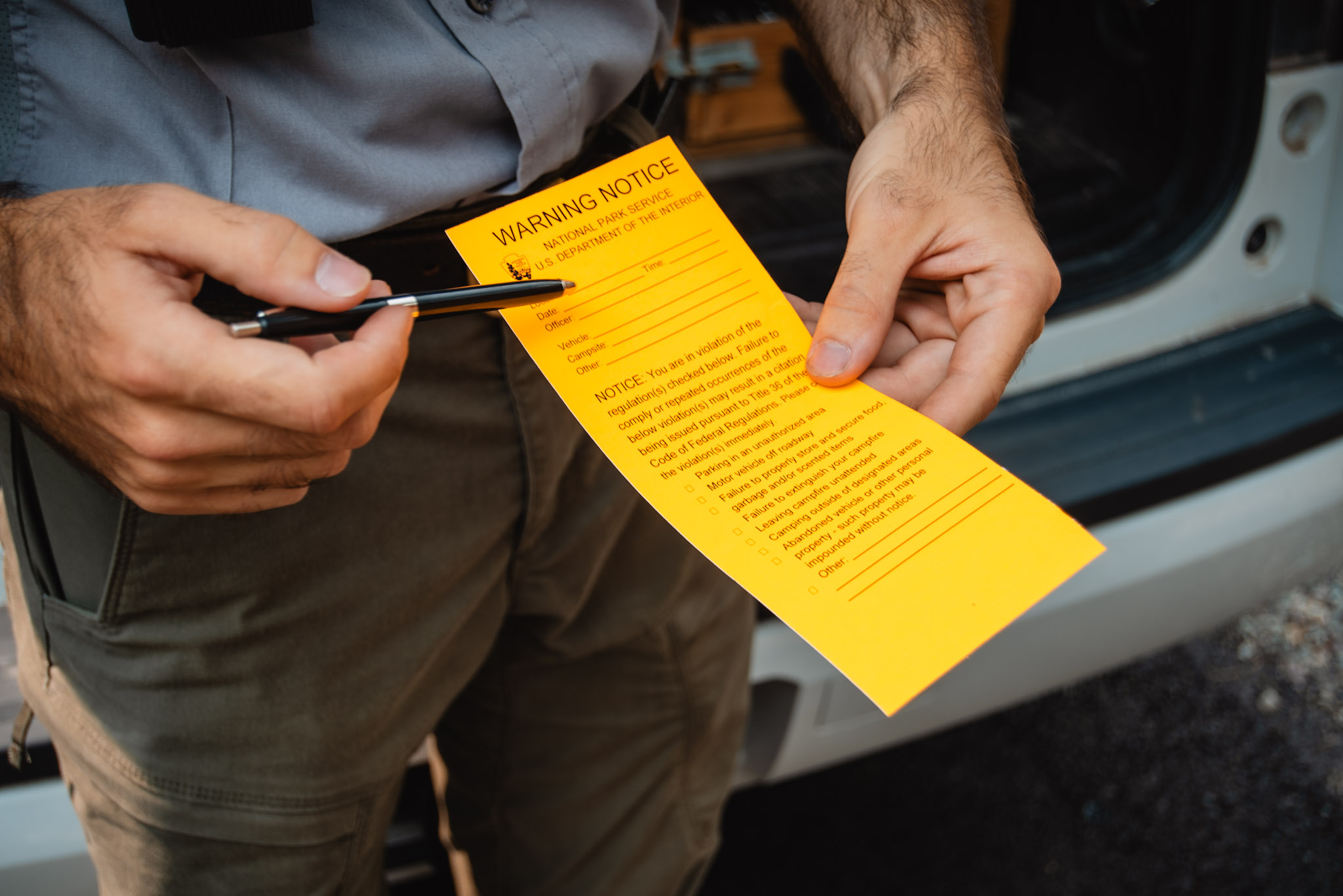 A ranger points to a warning notice.